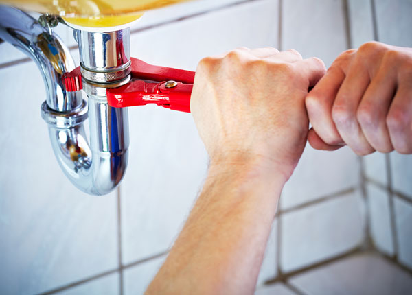 Plumber tightening a pipe fitting with a wrench