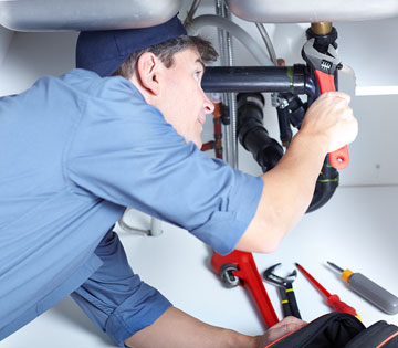 Plumber repairing a pipe under a sink